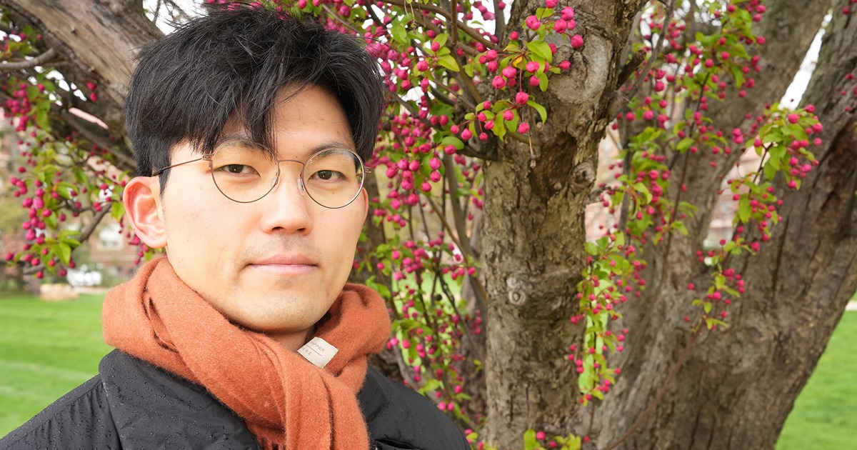 Close-up of Hunsoo Song in front of the pink blossoms of a crabapple tree