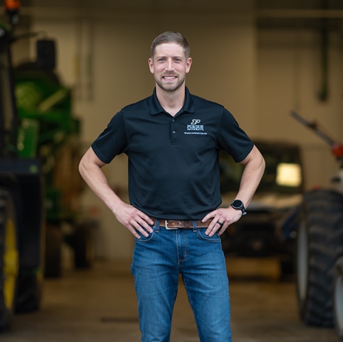 Tyler Finley stands in front of tractors 