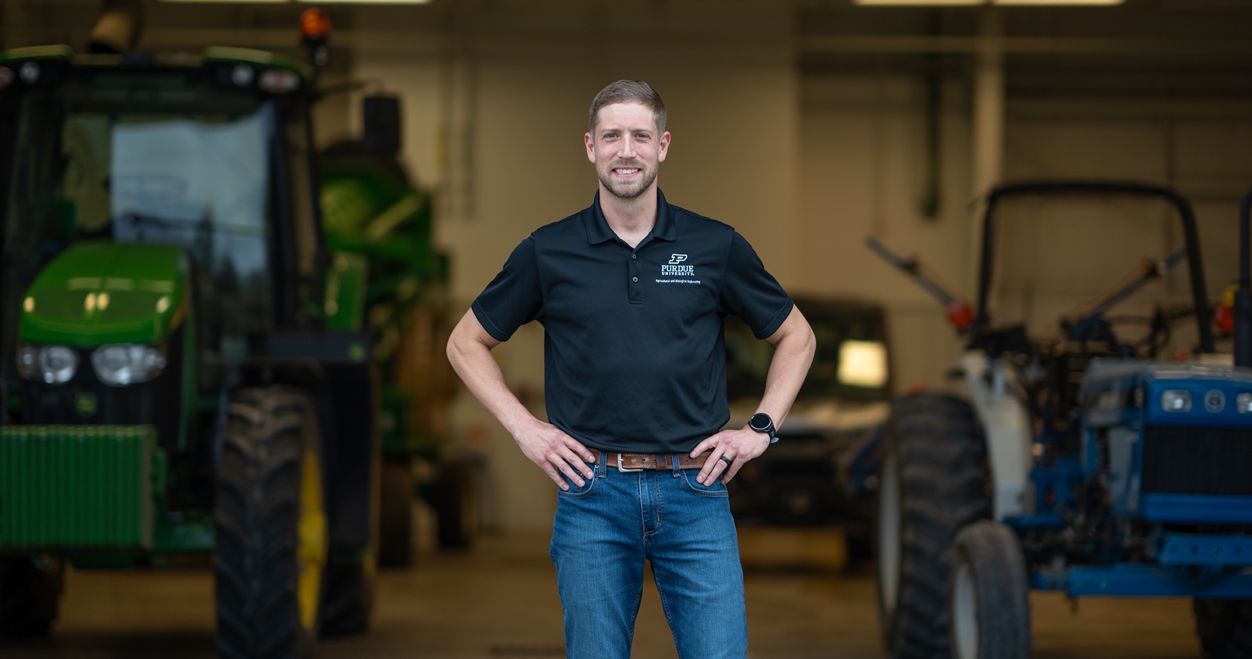 Tyler Finley stands in front of tractors 