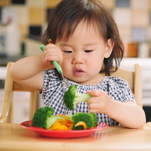 Young girl eating vegetables 