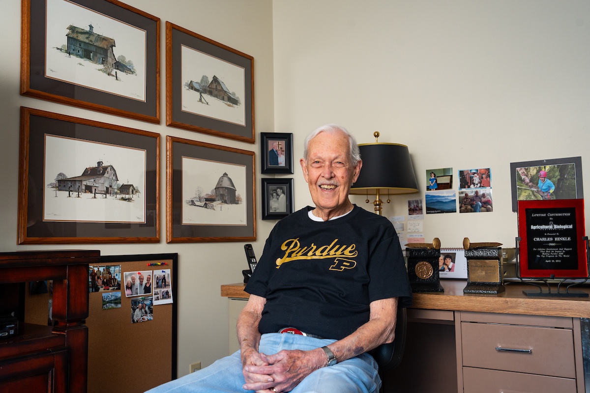 Charles (Chuck) Hinkle in his apartment, framed illustrations of barns in the walls