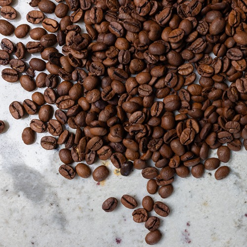 brown coffee beans scattered across a gray marble countertop