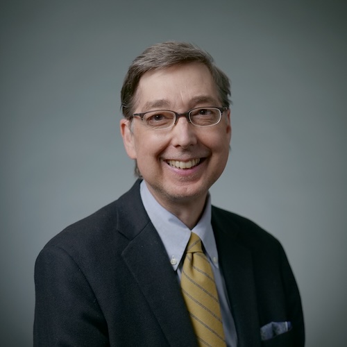 Picture of Jerry Shively smiling in front of grey background.