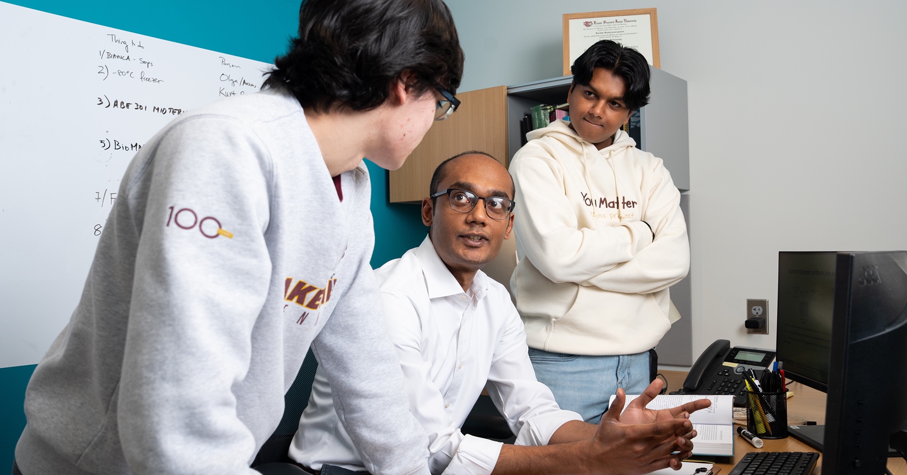 Students work with professor at computer in Purdue lab.