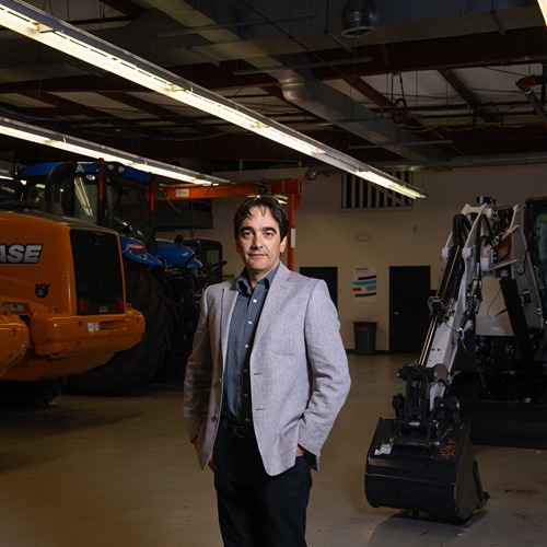 andrea vacca stands in Maha facility in front of construction vehicles