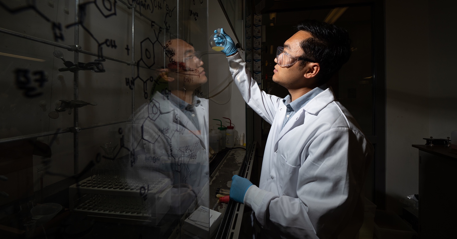 Jinhong Chen, a postdoctoral scientist at Purdue, examines the reaction mixture for synthesizing a Cdc14 inhibitor. 