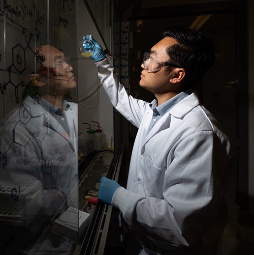 Jinhong Chen, a postdoctoral scientist at Purdue, examines the reaction mixture for synthesizing a Cdc14 inhibitor. 