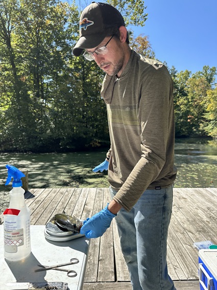 Tyler Hoskins measures a fish sample.