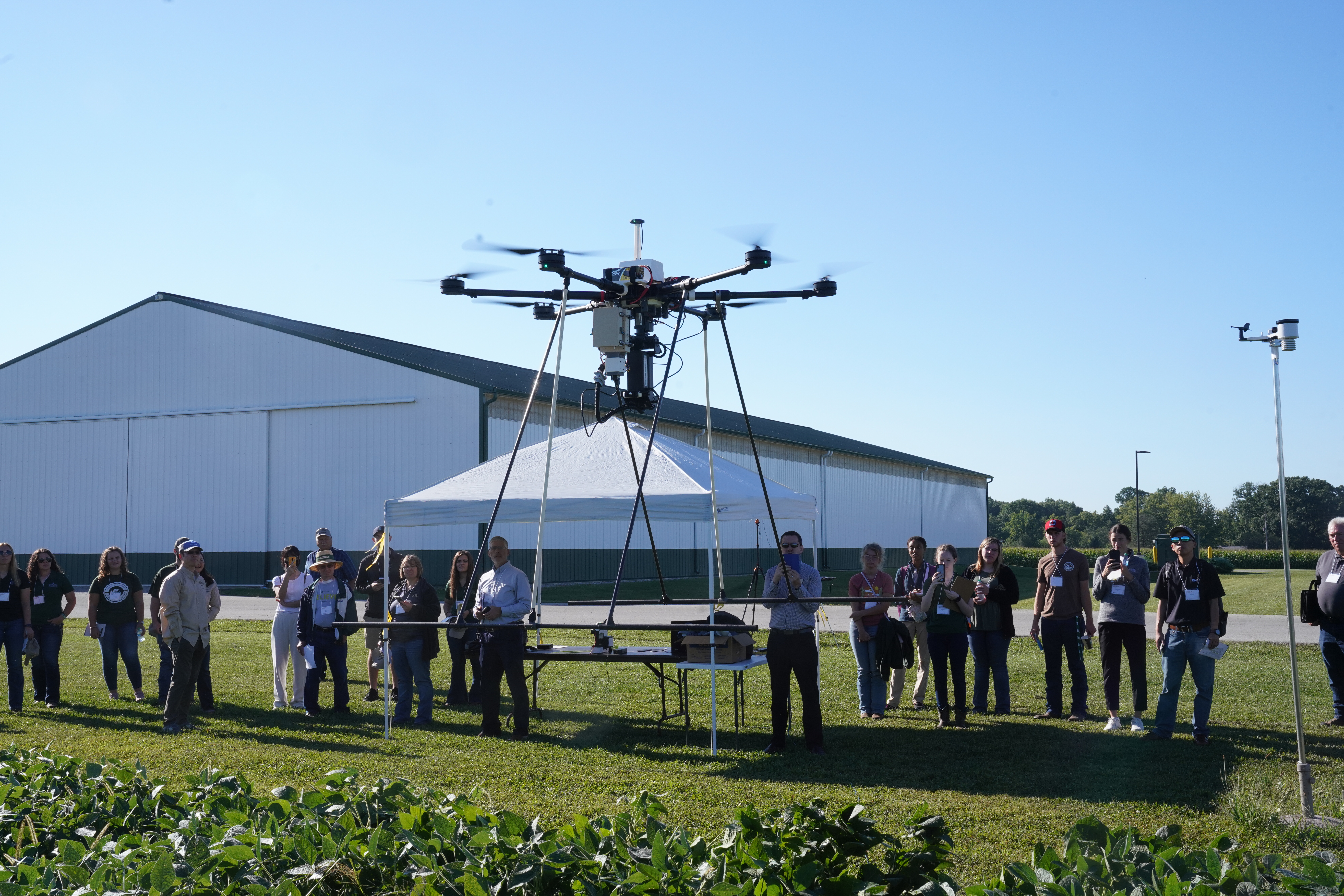 Attendees of the Digital Agriculture Showcase at Agronomy Center for Research and Education watching a drone prepare for flight.
