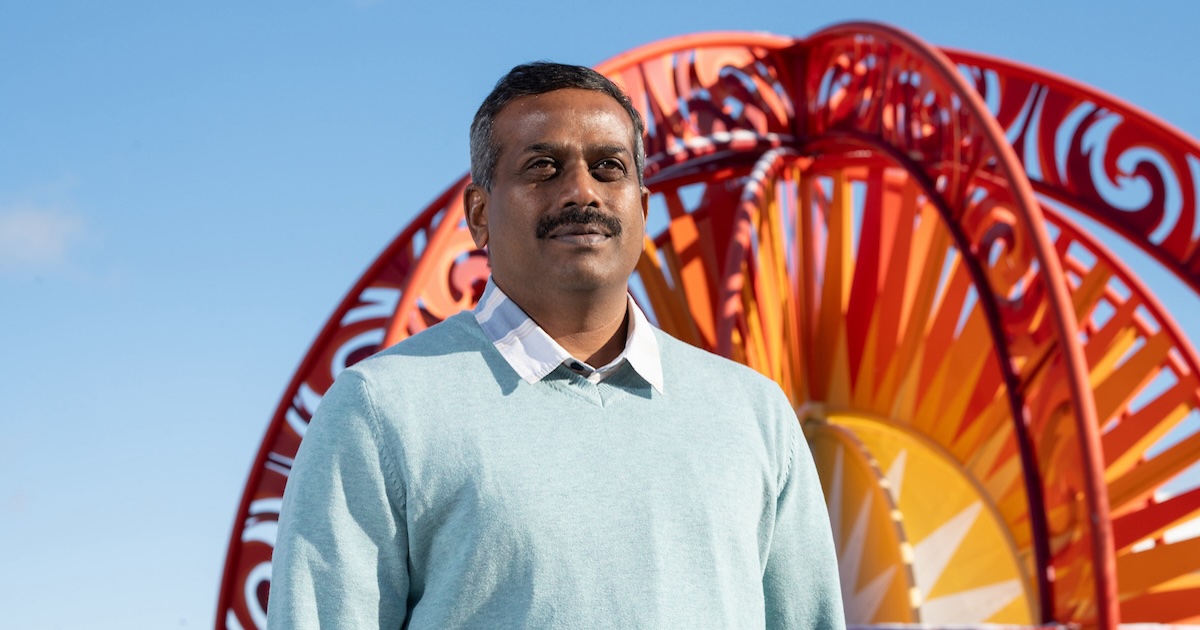 Kingsly Ambrose in front of the solar system model in Discovery Park on campus.
