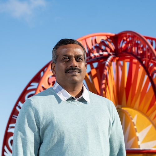 Kingsly Ambrose in front of the solar system model in Discovery Park on campus.