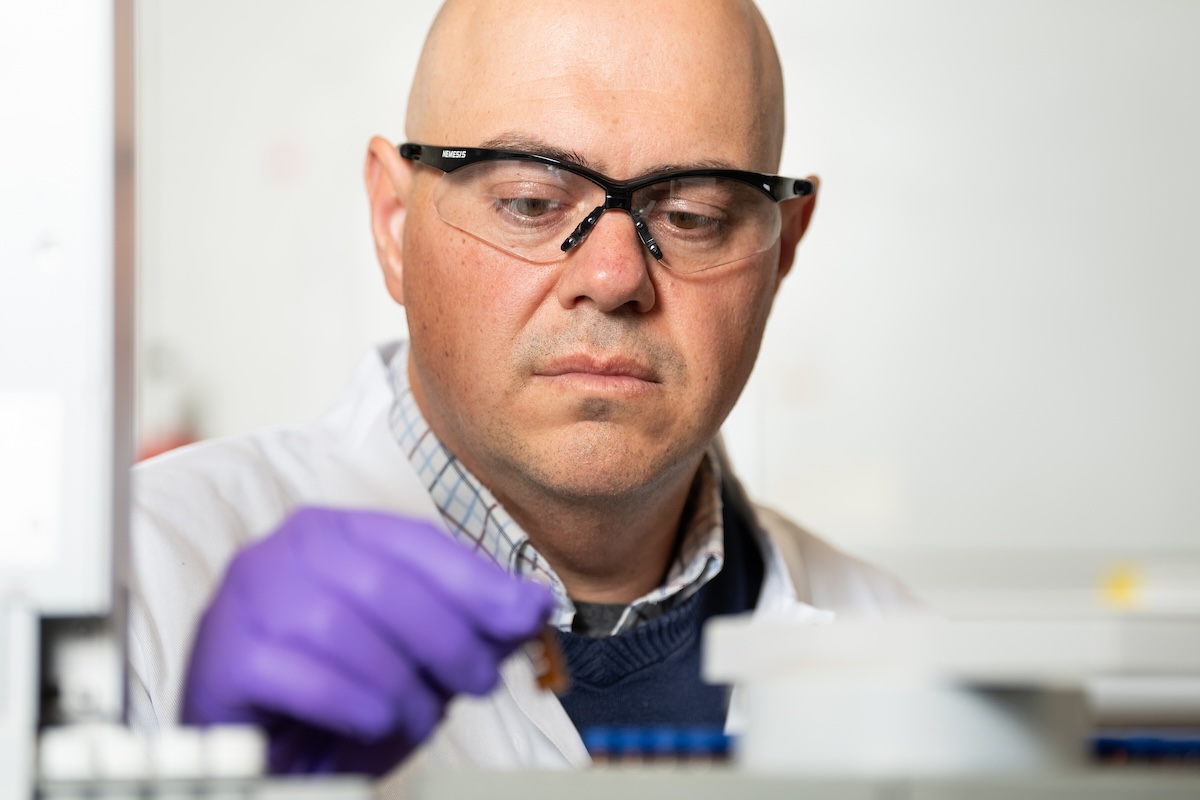 A man wearing safety goggles and white lab coat