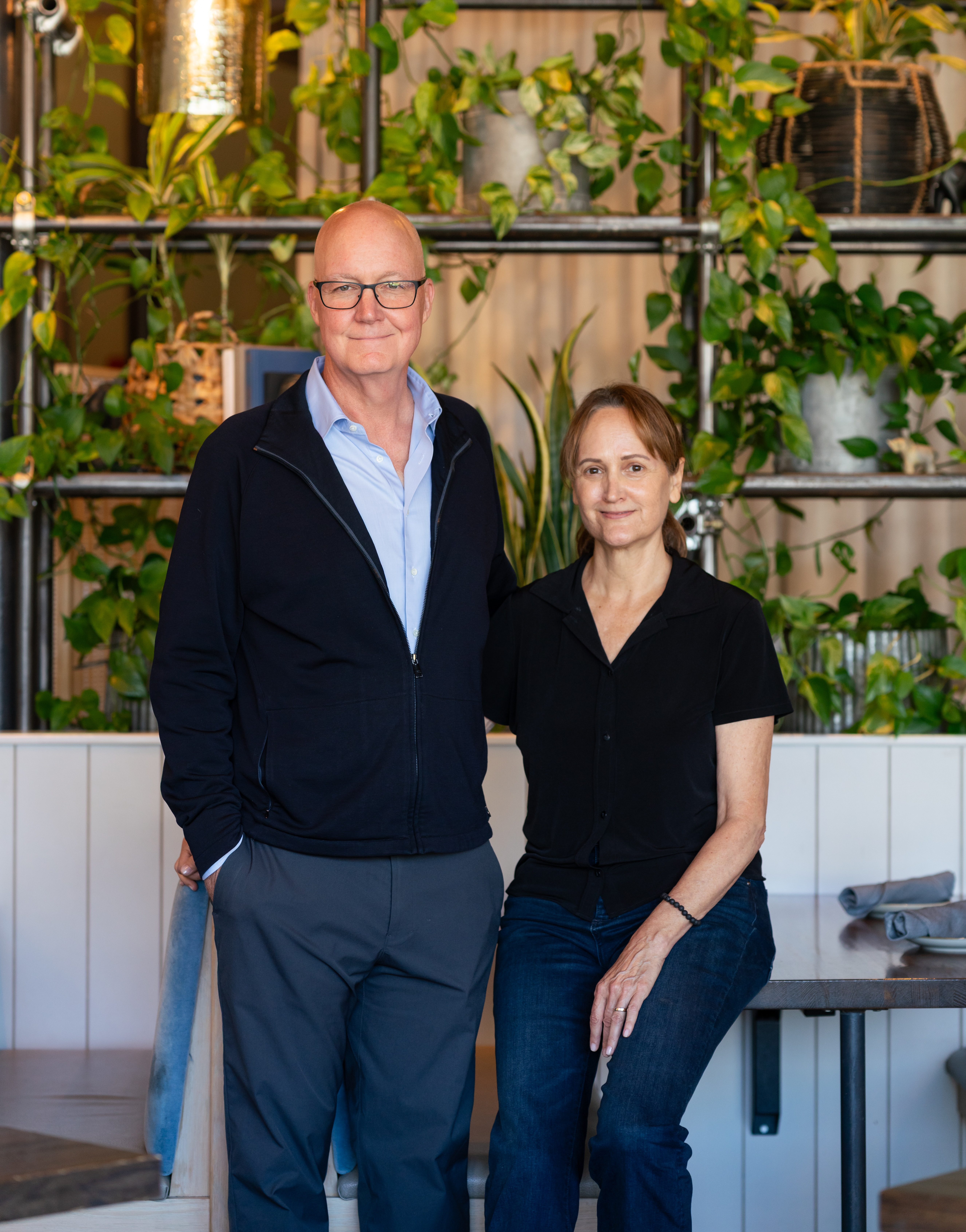 Bill and CD Young at a table in front of greenery in the Spirit and Elephant restaurant.