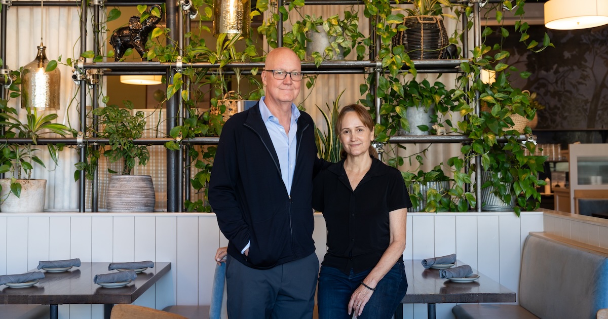 Bill and CD Young at a table in front of greenery in the Spirit and Elephant restaurant.