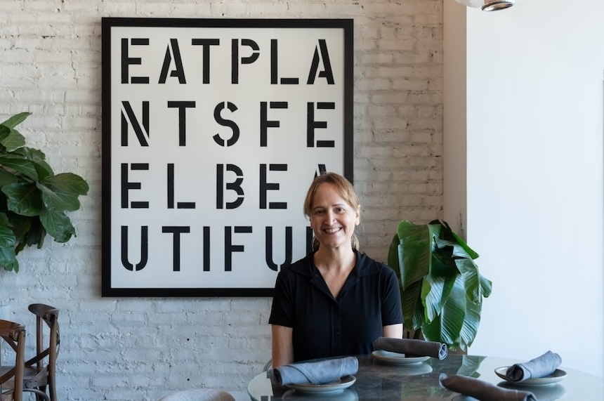 CD Young in front of a sign that reads "EAT PLANTS FEEL BEAUTIFUL."