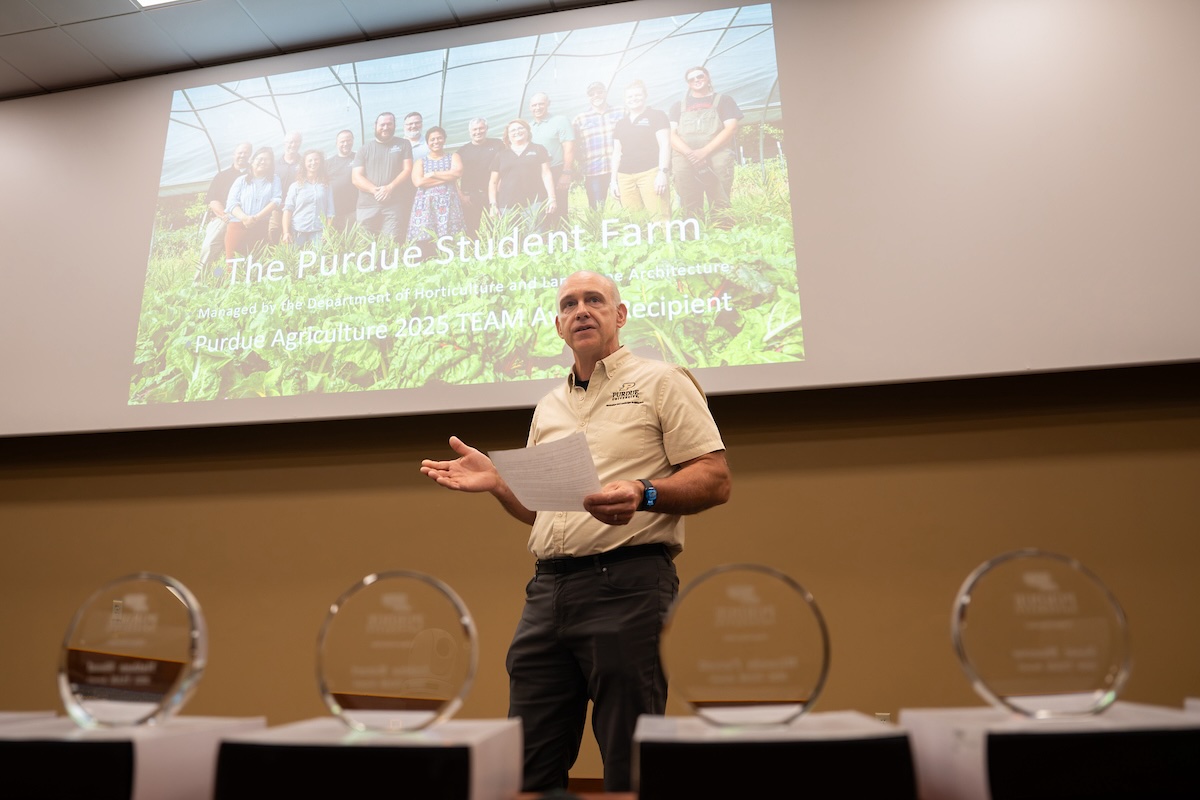 Petrus Langenhoven in front of a screen that reads "The Purdue Student Farm" with four awards in the foreground.