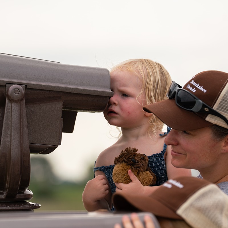 A mom and toddler look through binoculars