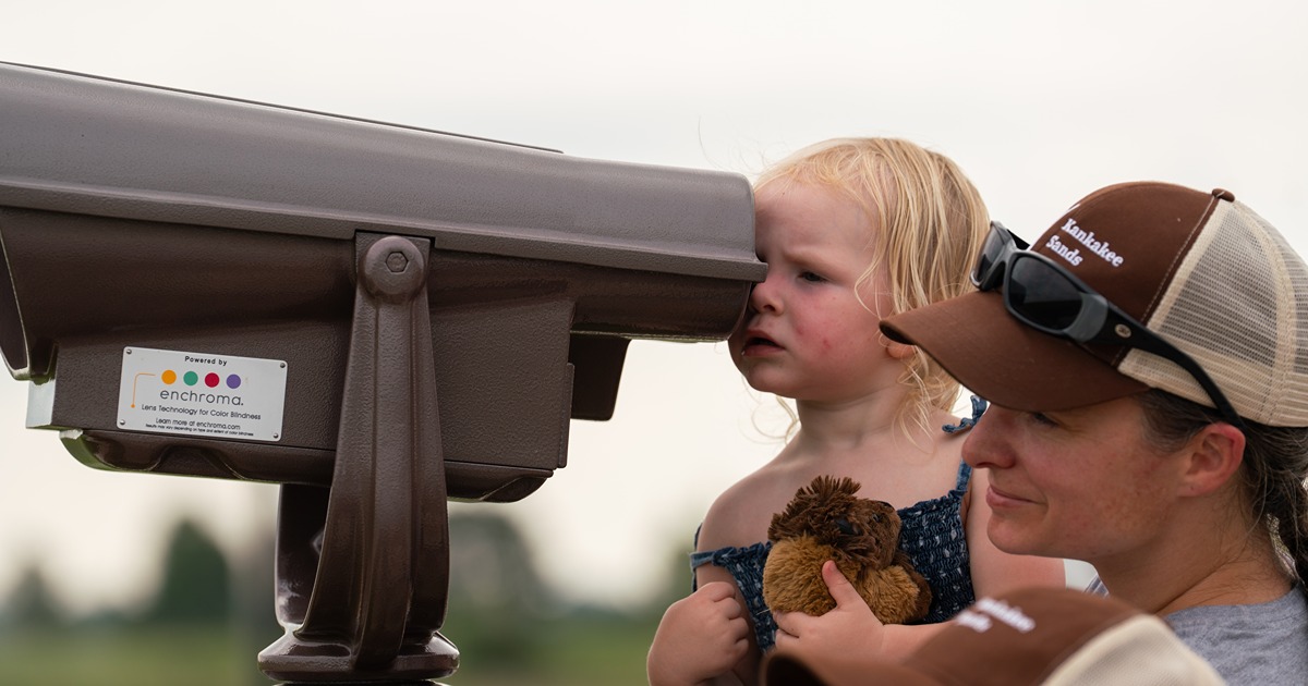 A mom and toddler look through binoculars
