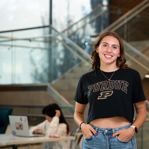 Meghan Haws in a Purdue T-shirt posing in front of a staircase