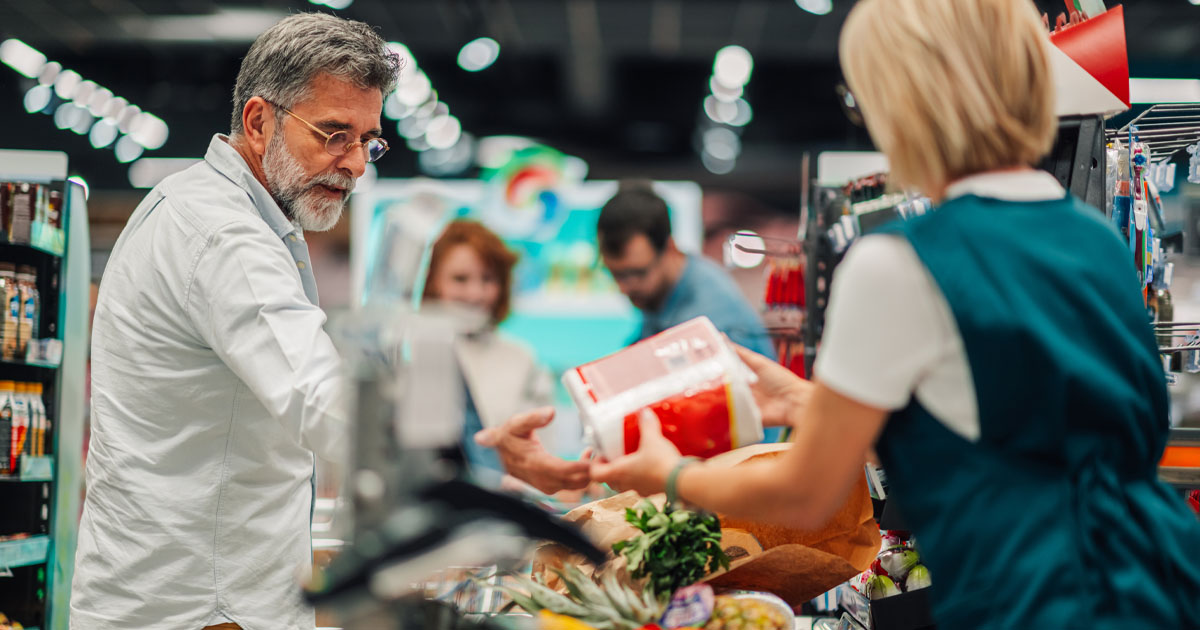 Customer unloading groceries at checkout and cashier.