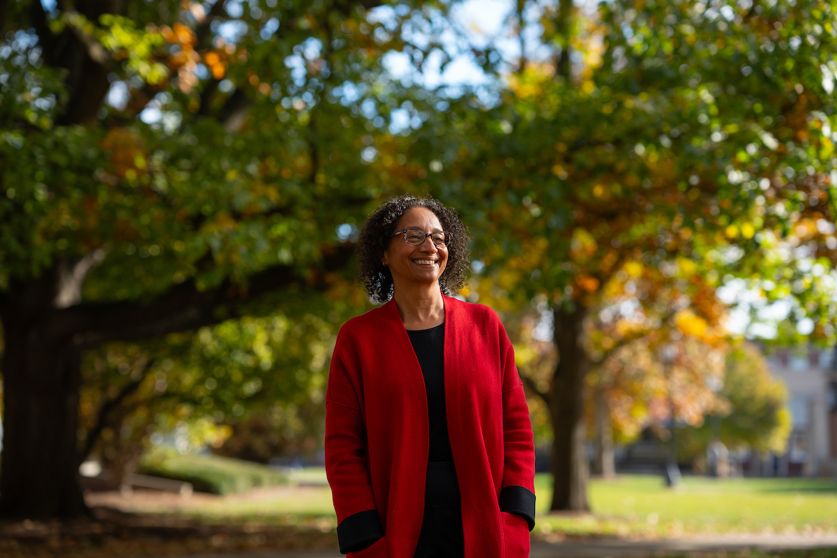 Maria Marshall standing in front of trees on campus and looking into the distance smiling.