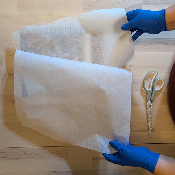 hands holding parchment paper above a book