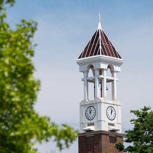 Purdue University's bell tower at the West Lafayette campus with greenery in the foreground.