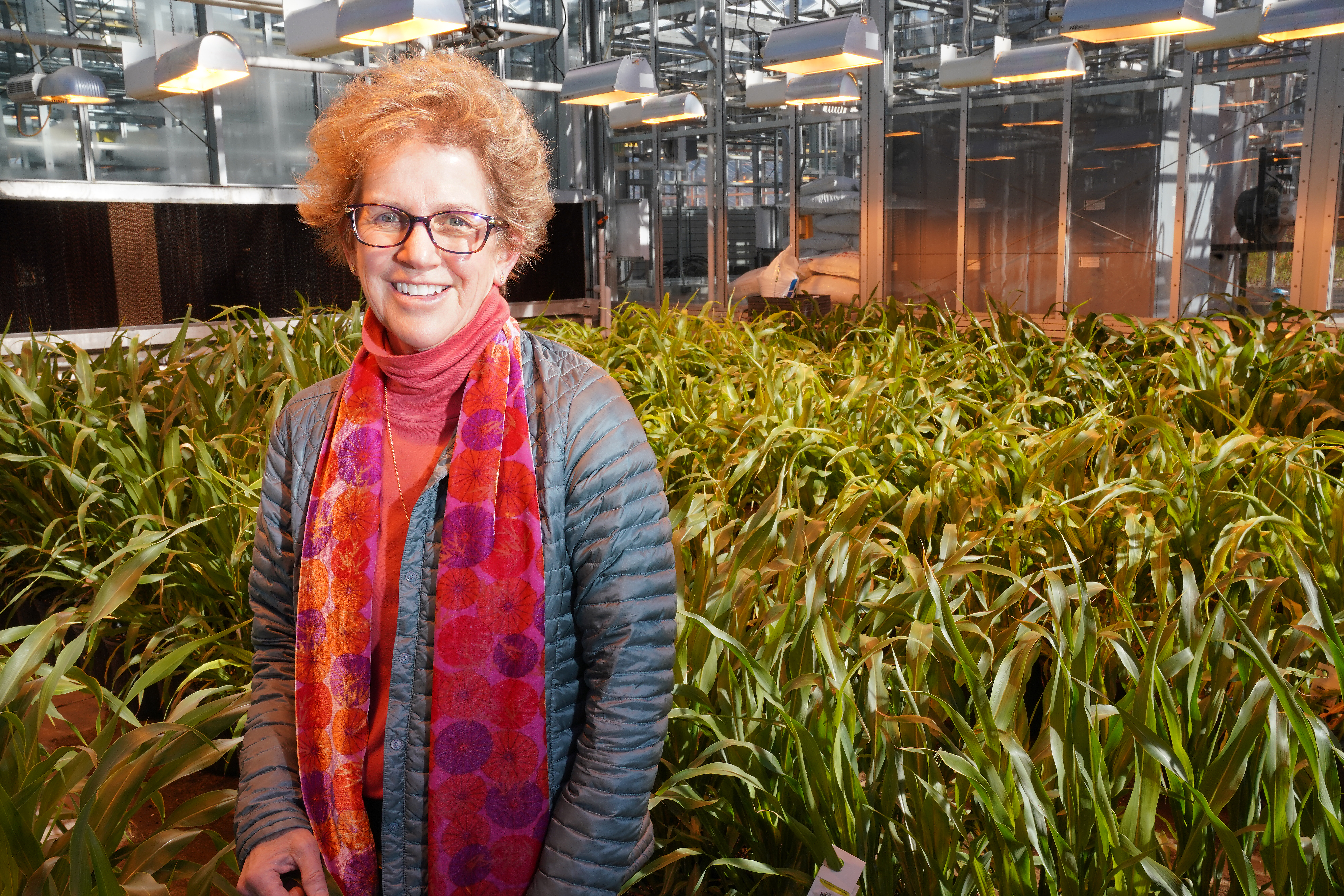 Sylvie Brouder inside a greenhouse with greenery in the background.