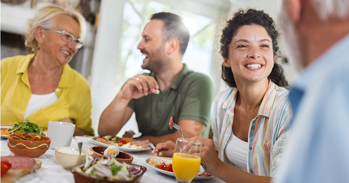 Four adults talking at a table with healthy food 