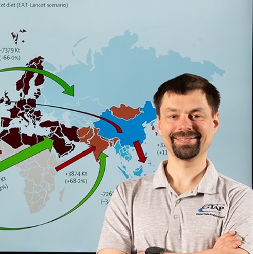 Economist stands before global food loss and waste export map.