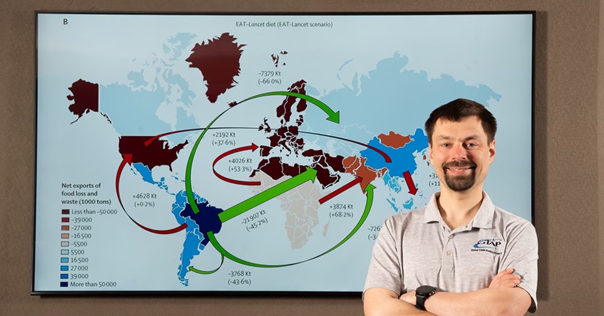 Economist stands before global food loss and waste export map.