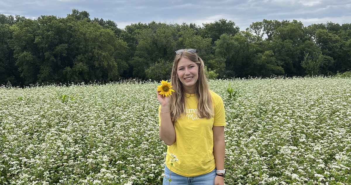 Monica Stampfli in a field holding a sunflower.