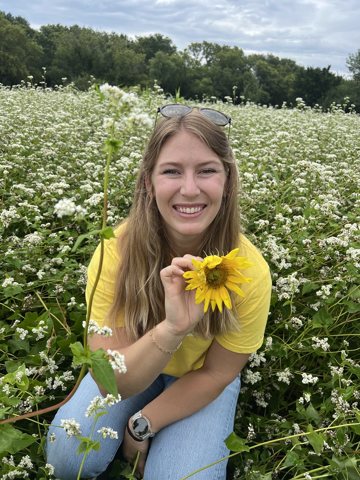 Monica in a field holding a sunflower