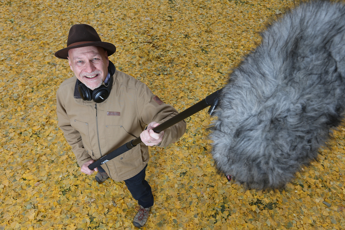 Image of Bryan Pijanowski on leafs holding big microphone to record sounds of nature.