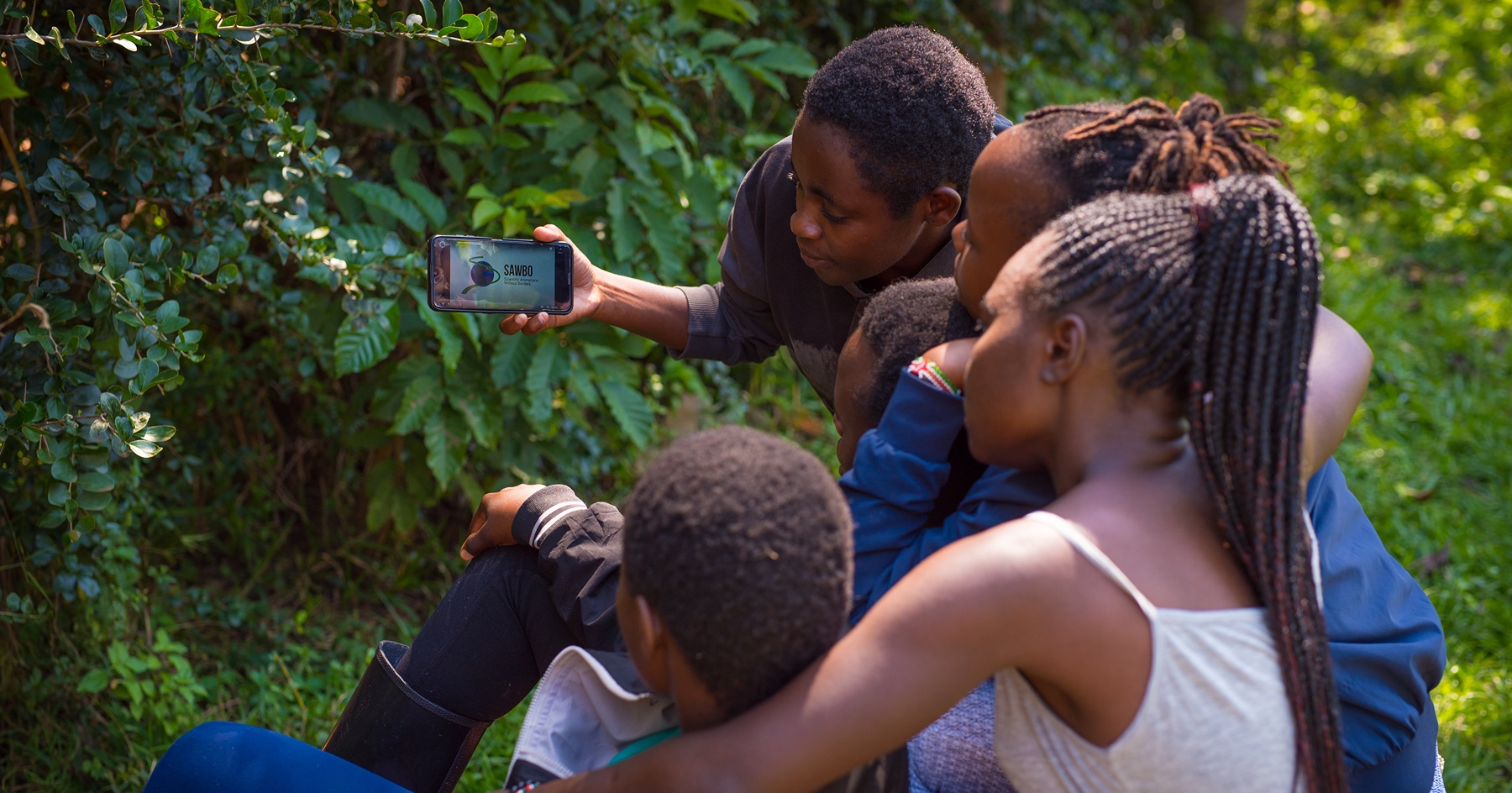 A group of people holding a cell phone with the SAWBO app open. 