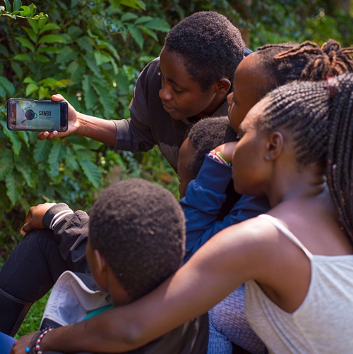 A group of people holding a cell phone with the SAWBO app open. 