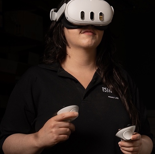 A woman wearing virtual reality glasses engages with a computer screen.