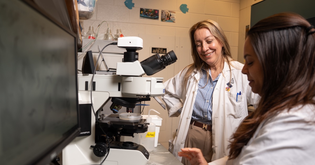 Andrea Liceaga with a graduate student in a lab looking at a microscope
