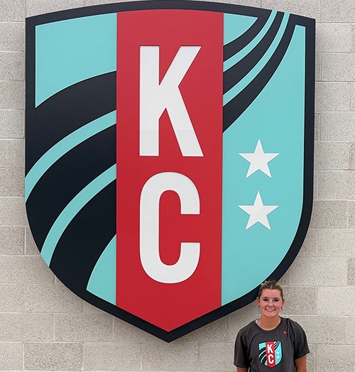 Bailey Arbic in front of Kansas City Current sign.