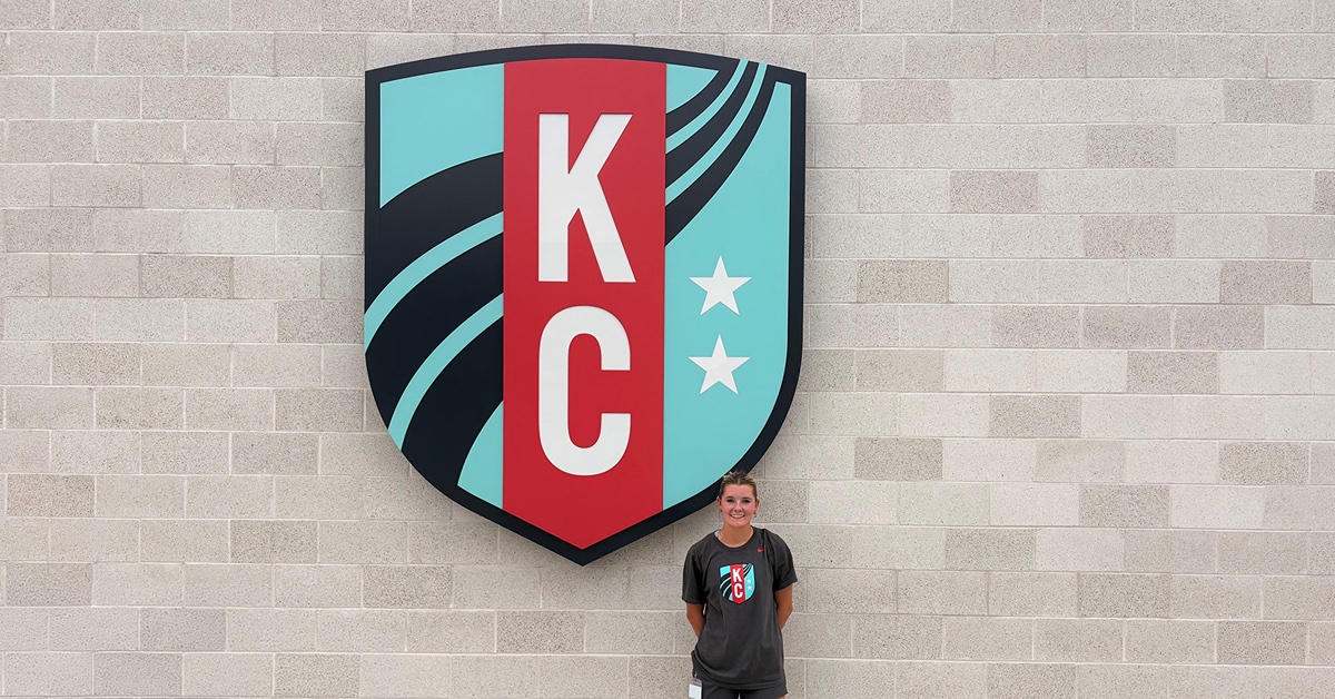 Bailey Arbic in front of Kansas City Current sign.
