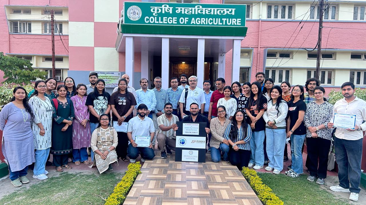 Nemali and students outside of a red brick building with an awning that reads, "College of Agriculture."