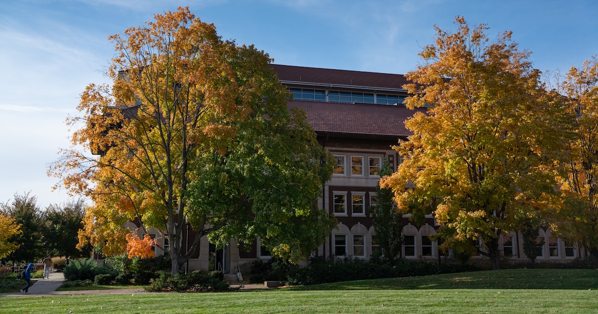 Red brick building on Purdue University's campus with two yellow and orange trees on either side.