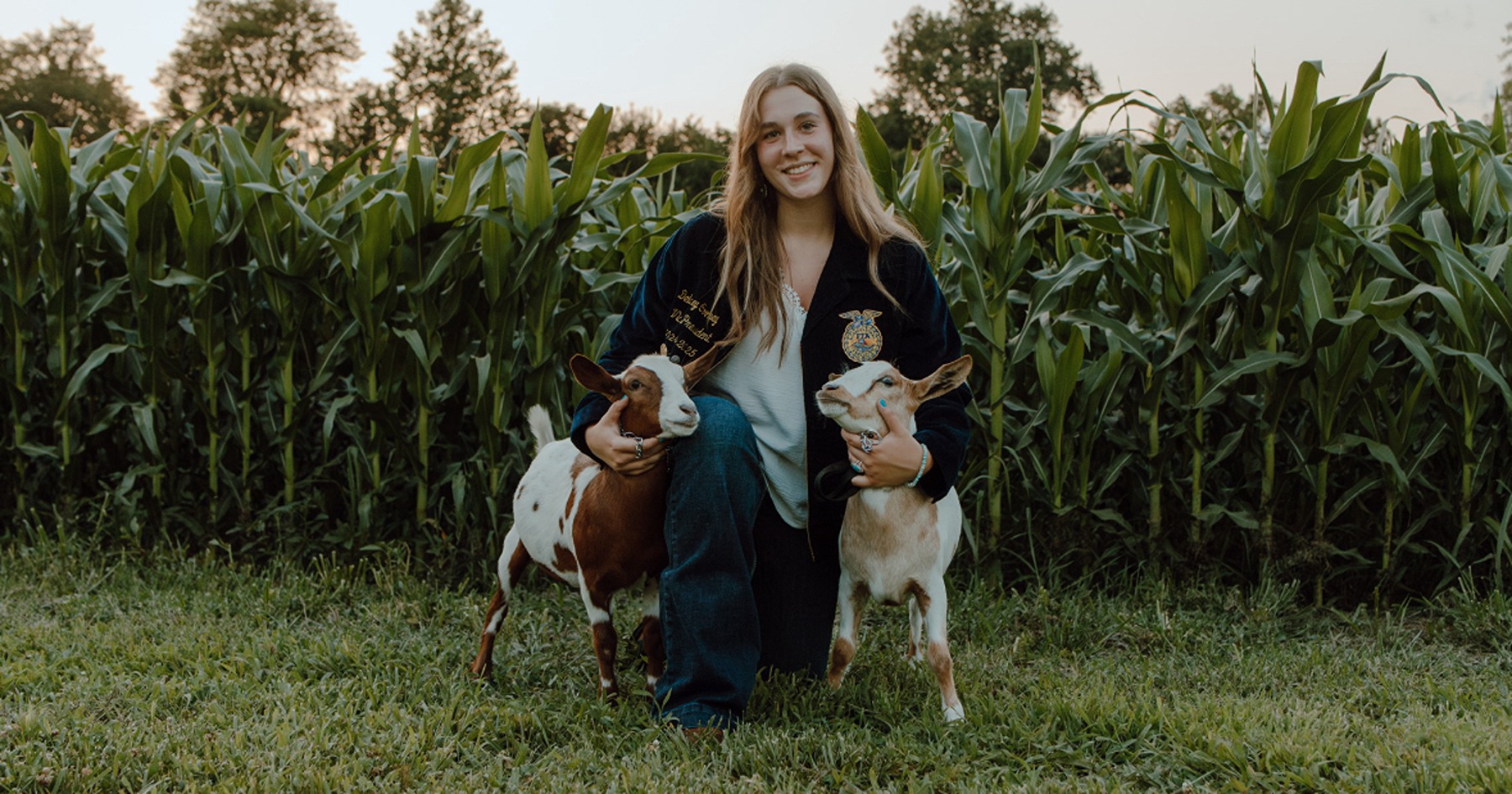 Delaney Cooney poses with goats near corn field