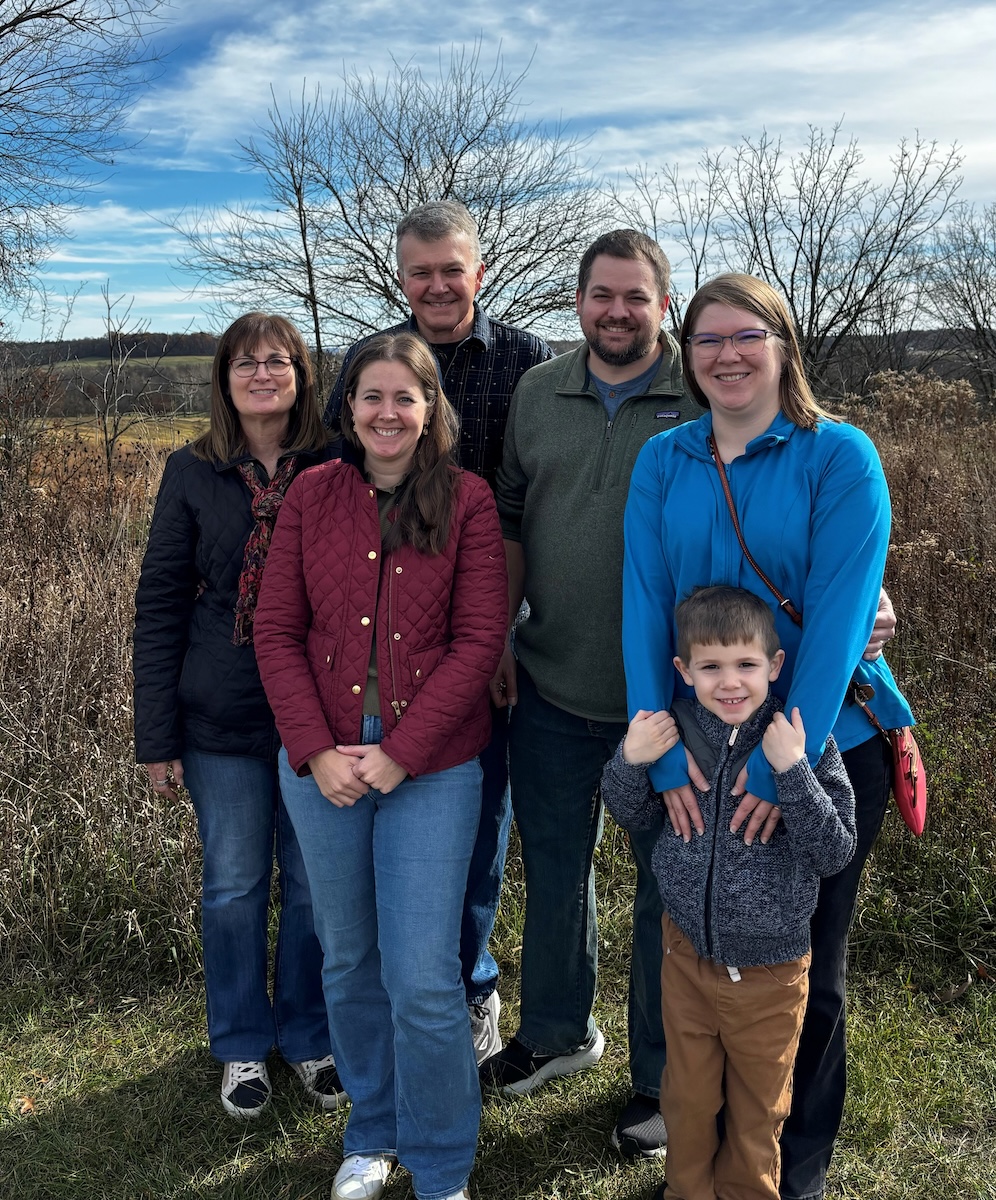 A three generation family stands together in a rural setting