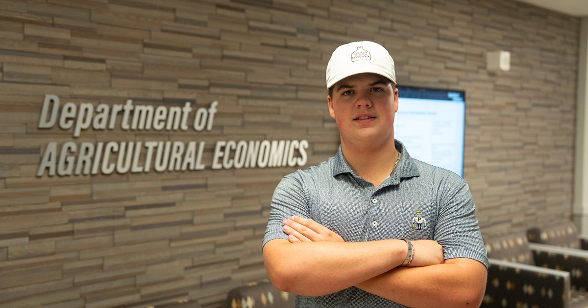 Brody Cox poses in front of Agricultural Economics sign
