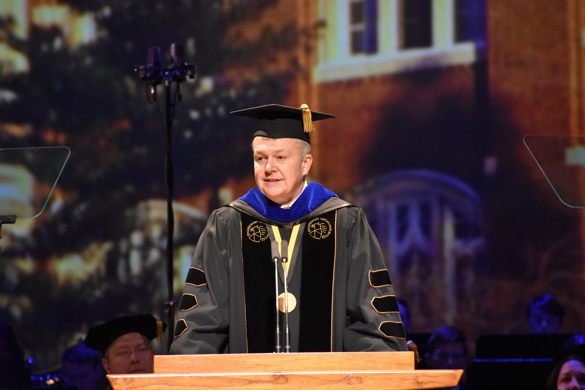Man stands behind podium at commencement