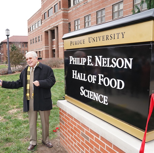 Phil Nelson standing in front of the building named after him at Purdue University.
