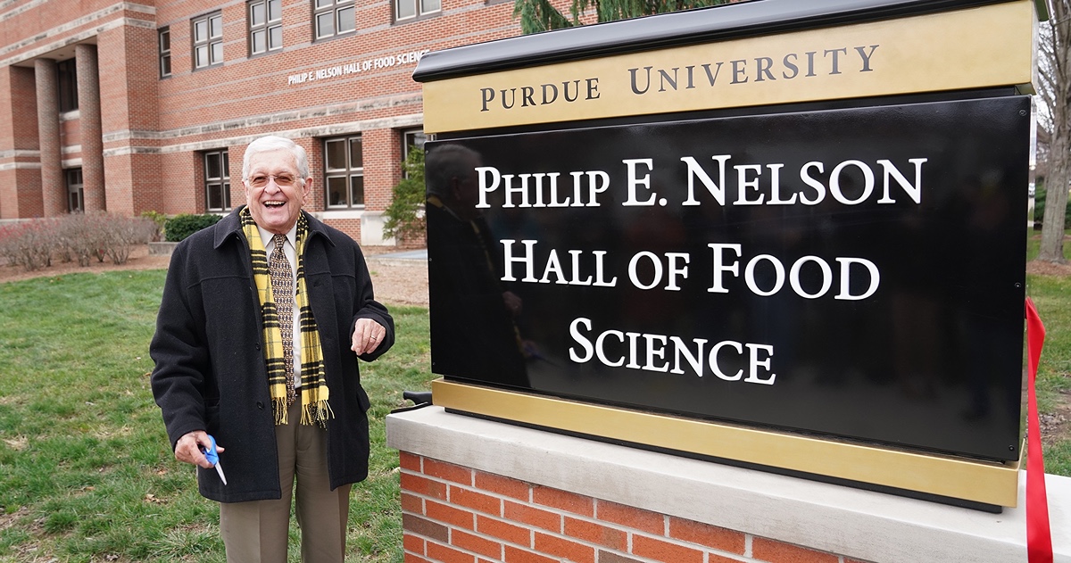Phil Nelson standing in front of the building named after him at Purdue University.