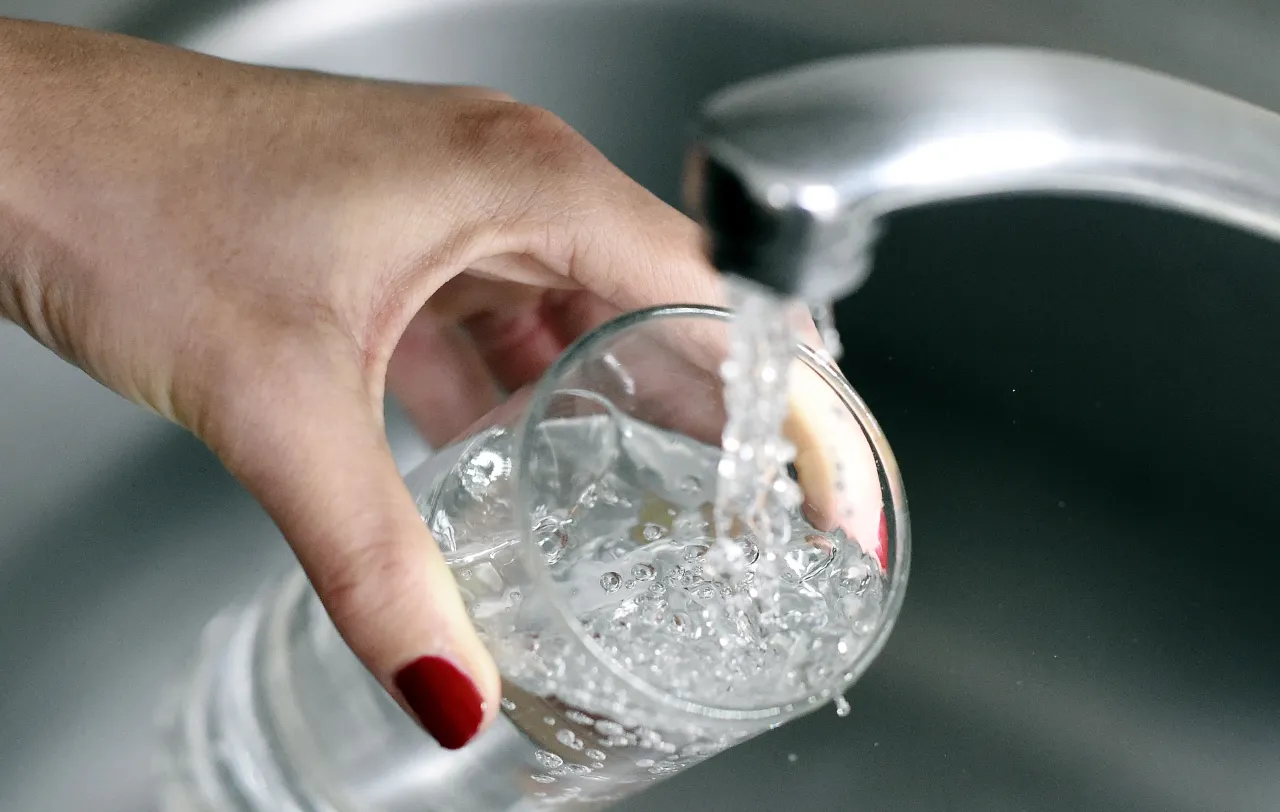 hand holding cup under water faucet