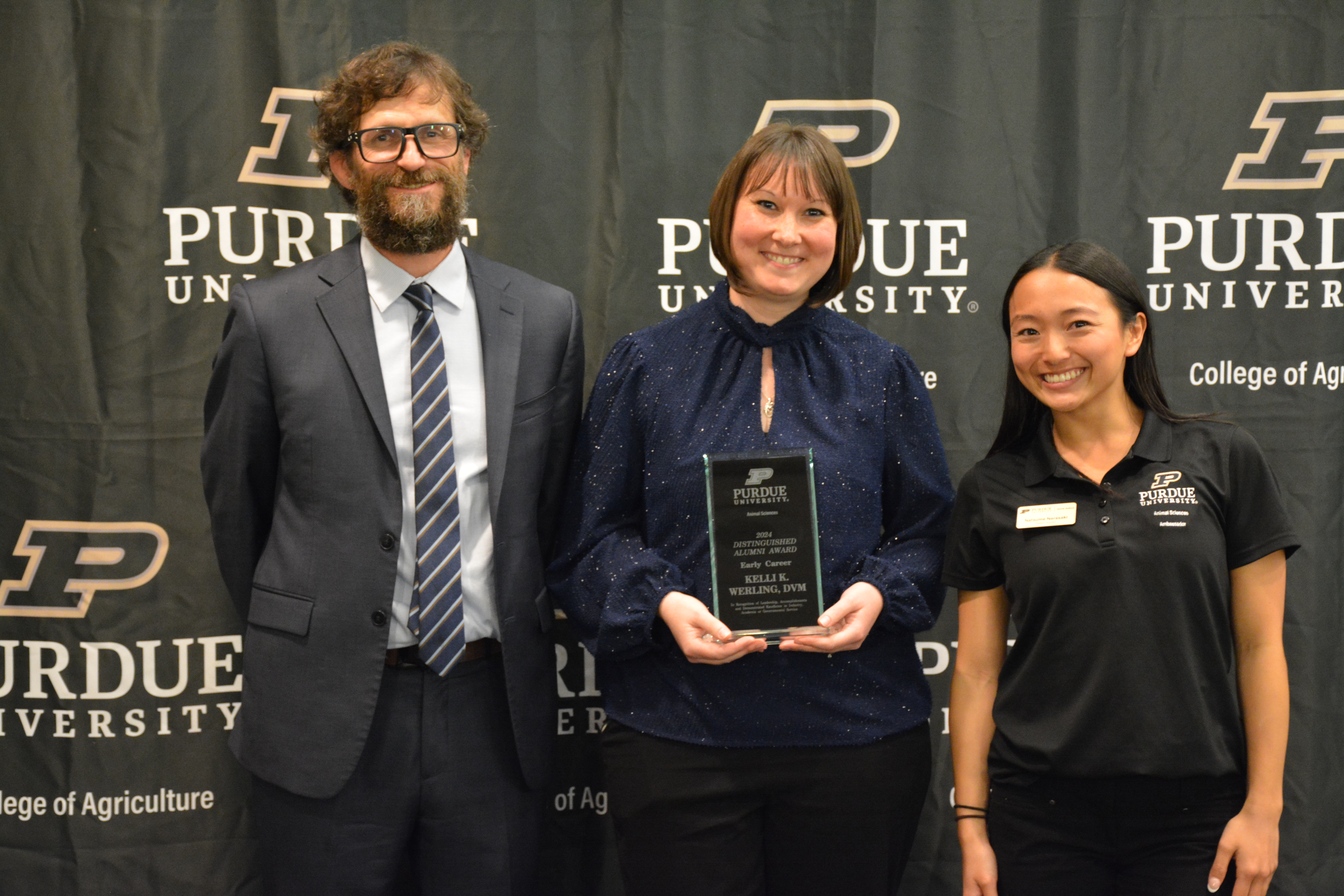 Dr. Kelli Werling accepting her award. Dr. Paul Ebner and Natsume Narasaki stand next to her.